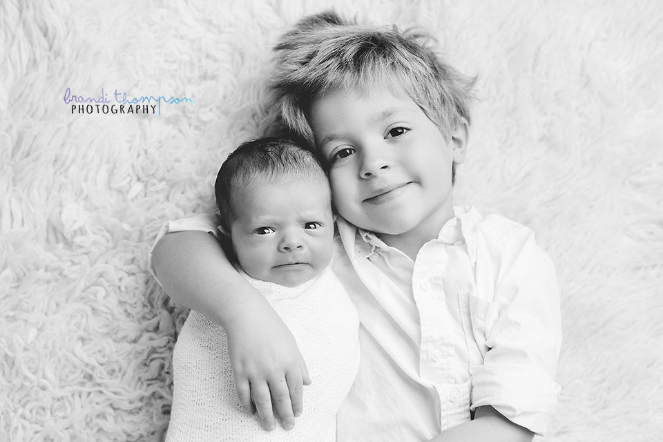 newborn photography - black and white image of newborn baby with eyes open and older brother